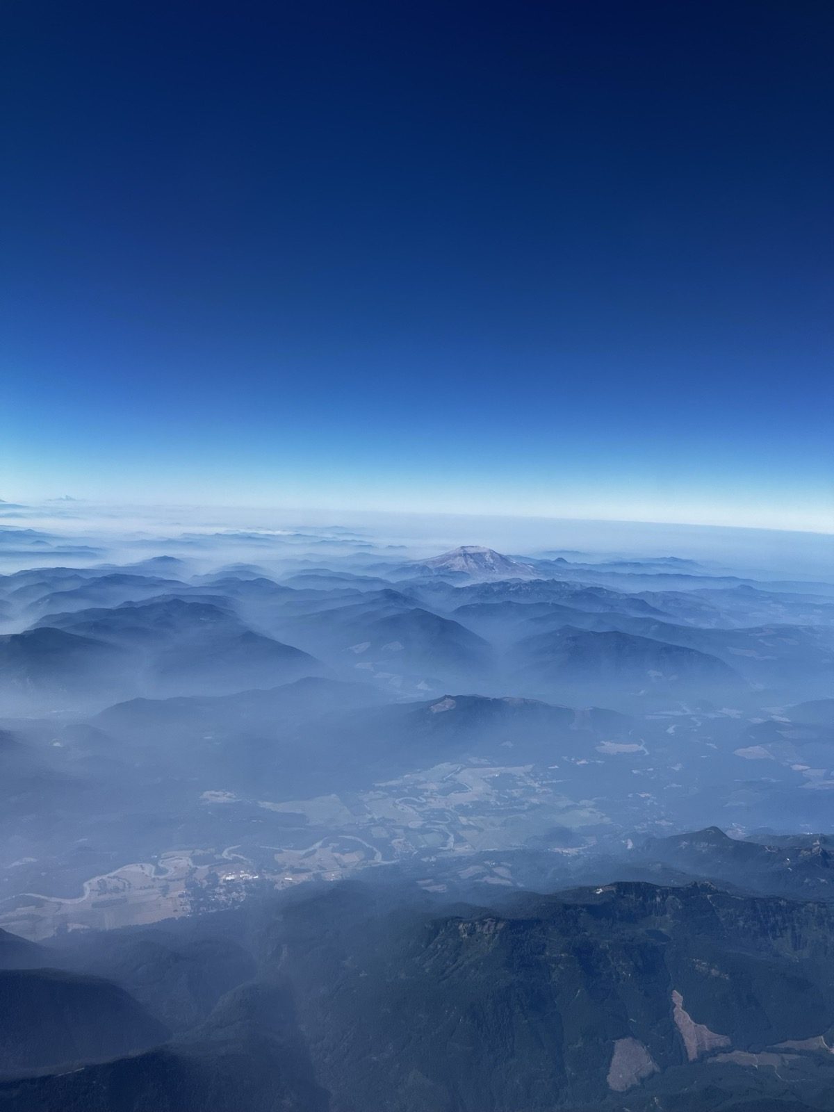 Layered ridgelines seen from above, fading into haze